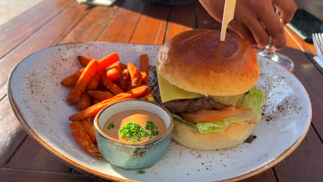 Yummy-cheeseburger-with-a-brioche-bun-and-sweet-potato-fries-with-spicy-mayonnaise-sauce,-restaurant-experience,-4K-shot