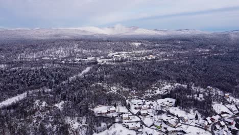Amazing-view-of-snow-covered-rural-area,-village-and-road-in-the-winter-forest,-Slovenia-drone