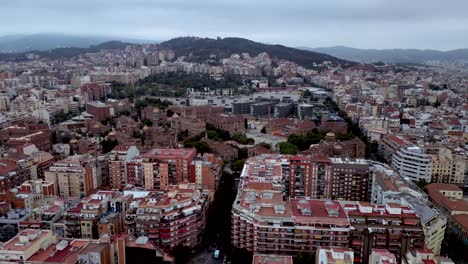Eine-Filmische-Luftdrohnenaufnahme-Der-Stadt-Barcelona-Mit-Hochhäusern,-Gewerbe--Und-Wohngebieten-Und-Dem-Blick-Auf-Die-Pyrenäen-Im-Hintergrund