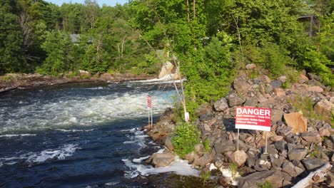 Drone-flight-passes-over-the-water-through-the-outlet-of-a-dam-and-the-warning-signs