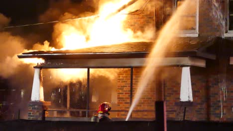 Firefighters-try-to-extinguish-a-burning-house-at-night