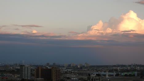Zeitrafferansicht-Der-Wolkenlandschaft-Von-Weißen,-Flauschigen-Wolken,-Die-Sich-Im-Wind-über-Der-Skyline-Einer-Stadt-Bewegen,-Bei-Sonnenuntergang