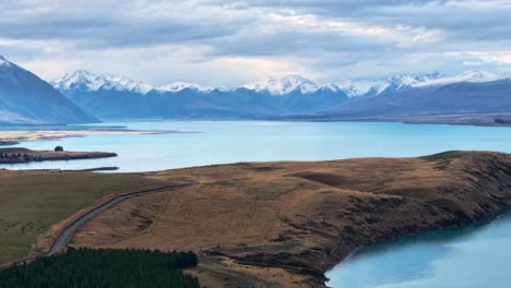 Timelapse-of-clouds-passing-above-snowy-mountain-range-at-Lake-Tekapo,-New-Zealand-aerial-view