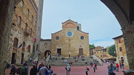 Person-Walking-To-The-Piazza-del-Duomo-With-Palazzo-Comunale-And-Cathedral-of-San-Gimignano-In-Italy