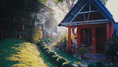 Exquisite-wooden-house-nestled-in-a-serene-garden,-adorned-with-sunlight-rays-casting-a-captivating-flare-on-the-rocky-road