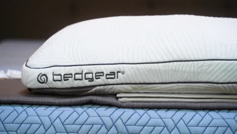 A-Brand-New-White-Bedgear-Logo-Performance-Technology-Cooling-Stain-Resistant-Pillow-Sleeping-Cushion-on-a-bed-inside-a-mattress-store