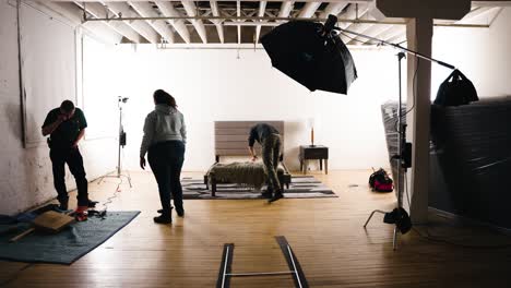 Timelapse-Multiple-People-setting-up-Commercial-Assembling-Furniture-a-Bed-Frame-Backstage-Inside-a-Professional-Hard-Wood-Photography-Film-Set-Studio-Surrounded-by-Bright-Lights-Softbox