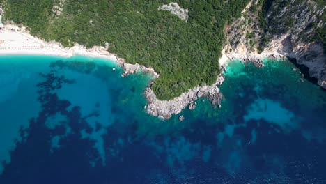 Unspoiled-coastline-of-Ionian-sea-in-Albania-with-caves-on-cliffs-washed-by-deep-blue-turquoise-sea-and-beautiful-beaches-with-white-sand