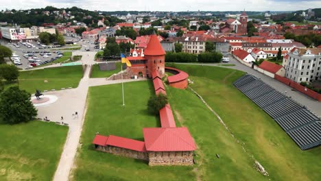 Drone-shot-of-the-historic-old-red-brick-Kaunas-Castle-with-Ukrainian-flag-in-Kaunas-old-town,-Lithuania,-parallax-shot
