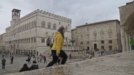A-lone-female-walks-past-the-Piazza-IV-Novembre-and-along-the-stairs-outside-the-Perugia-Cathedral-in-Perugia,-Province-of-Perugia,-Italy