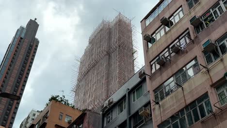 Tagesaufnahme-Eines-Hochhauses-In-Hongkong-Mit-Bambusgerüsten-Und-Düsterem-Himmel