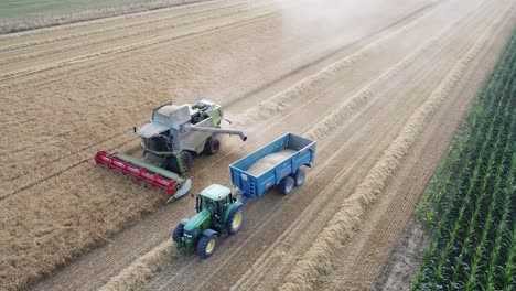 A-cinematic-4K-drone-shot-of-a-combine-harvester-and-a-tractor-harvesting-a-field-in-France,-showcasing-agriculture-with-an-epic-view-and-dramatic-dust