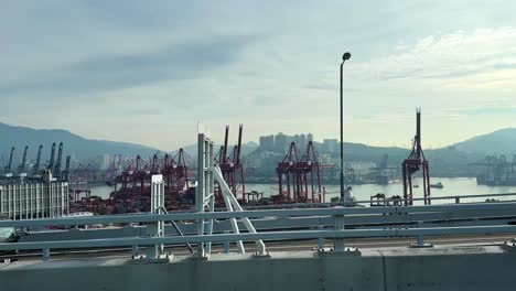 Vorbeifahrende-Ansicht-Des-Verschiffungshafens-Von-Hongkong-Mit-SF-Express-Lieferwagen,-Portalkränen-Und-Containern-Von-Der-Autobahnbrücke