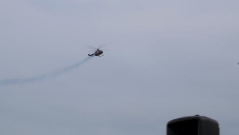 RedBull-BO-105-aerobatic-helicopter-demonstrating-stunts-at-Baltic-International-Airshow,-blue-smoke-trail,-handheld-shot,-4k