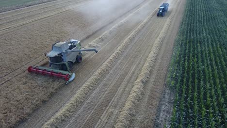 A-cinematic-4K-drone-shot-of-a-combine-harvester-and-a-tractor-harvesting-a-field-in-France,-showcasing-agriculture-with-an-epic-view-and-dramatic-dust
