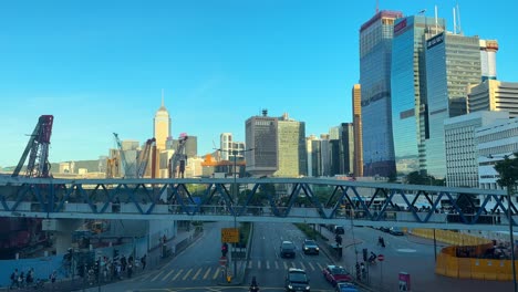 Crowd-Walking-on-Bridge-with-Traffic-Driving-Below-and-Modern-High-Rise-Skyline-in-the-Background-in-Hong-Kong