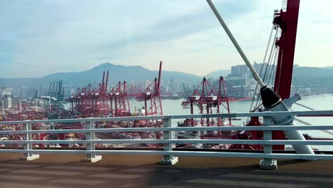 Blick-Vom-Auto-Auf-Die-Autobahnbrücke-Des-Geschäftigen-Hongkonger-Schifffahrtshafens-Mit-Portalkränen-Und-Gestapelten-Containern