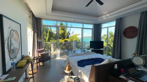 Daytime-Interior-of-Luxurious,-Slightly-Messy-Bedroom-with-King-Sized-Bed-and-Sunlit-Balcony-Overlooking-Palm-Trees-and-Ocean