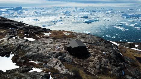 Un-Sinfín-De-Icebergs-Derritiéndose-Y-Edificios-Remotos-En-Groenlandia,-Vista-Aérea