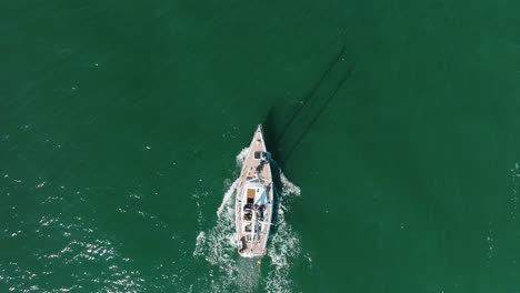 Aerial-establishing-view-of-a-white-sailboat-in-the-calm-Batltic-sea,-white-sailing-yacht-in-the-middle-of-the-boundless-sea,-sunny-summer-day,-wide-birdseye-done-tracking-shot-moving-forward