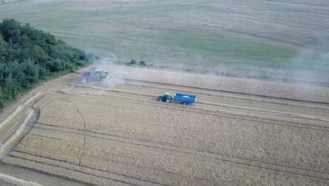 A-cinematic-4K-drone-shot-of-a-combine-harvester-and-a-tractor-harvesting-a-field-in-France,-showcasing-agriculture