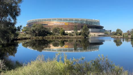 Optus-Perth-Stadium-on-a-bright-sunny-blue-sky-day-reflected-in-a-lake-at-Burswood-in-Western-Australia