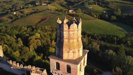 Aerial-view-over-a-medieval-castle-tower-on-top-of-a-hill,-surrounded-by-prosecco-vineyards,-in-Italy