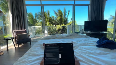 POV-of-Wealthy-Individual-with-Laptop-on-King-Sized-Bed-in-Luxurious-Bedroom-with-Open-Balcony-and-Palm-Trees