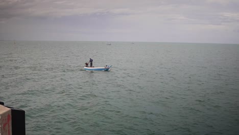 Offshore-Ansicht-Eines-Fischers,-Der-Auf-Einem-Kleinen-Fischerboot-Am-Pier-Von-Hua-Hin-Im-Golf-Von-Thailand-Steht