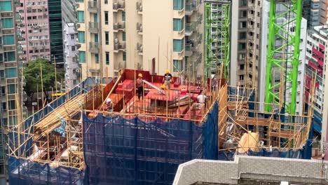 Bauarbeiter-Arbeiten-Auf-Dem-Dach-Eines-Neuen-Wohnhochhauses,-Umgeben-Von-Bambusgerüsten-In-Hongkong