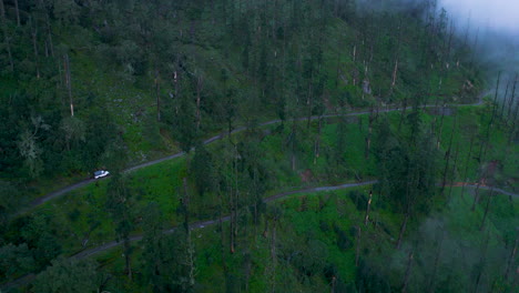 Un-Jeep-4x4-Viaja-Fuera-De-La-Carretera-En-Medio-Del-Paisaje-Forestal-De-Nepal,-árboles-Cubiertos-De-Niebla-Con-Nubes-En-La-Temporada-De-Monzones