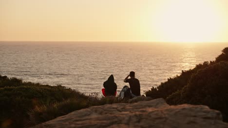 Romantisches,-Einfaches-Paar,-Das-Auf-Felsen-Sitzend-Einen-Sonnenuntergang-Am-Meereshorizont-Genießt