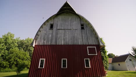 push-in-shot-of-an-old-red-and-white-barn-on-a-sunny-day-with-birds-flying