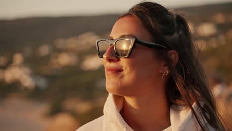 Face-of-caucasian-young-woman-with-sunglasses-enjoying-sea-breeze-at-sunset