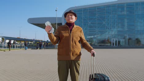 Senior-rich-pensioner-business-tourist-grandfather-stay-near-airport-hall-hold-money-dollar-cash