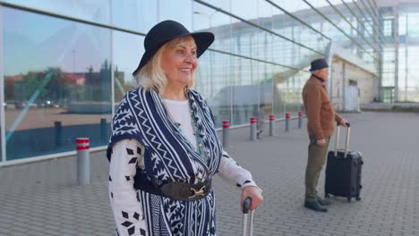 Senior-pensioner-tourist-grandmother-stay-near-airport-hall-celebrate-success-win-winner-gesture
