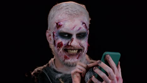Erschreckender-Mann,-Halloween-Zombie,-Der-Sein-Mobiltelefon-Benutzt-Und-Einen-Neuen-Beitrag-Im-Internet-Eingibt,-Surfen,-Sucht