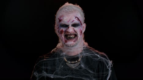 Zombie-man-with-wounds-scars-and-contact-lenses-looking-at-camera-clicks-his-teeth-trying-to-scare