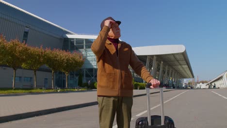Portrait-of-senior-retired-man-tourist-near-airport-terminal-waiting-boarding-on-plane-for-traveling