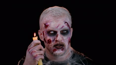 Mann-Mit-Blutigem,-Verwundetem-Halloween-Zombie-Make-up,-Der-Versucht-Zu-Erschrecken,-Zaubersprüche-über-Einer-Kerze