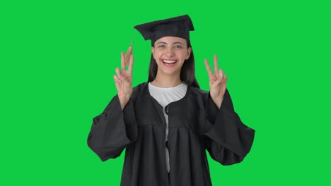 Glückliches-Indisches-Hochschulabsolventenmädchen,-Das-Siegeszeichen-Auf-Grünem-Bildschirm-Zeigt