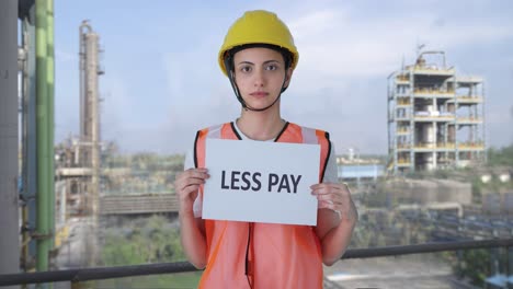 Sad-Indian-female-construction-worker-holding-LESS-PAY-banner