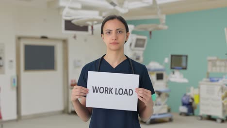 Sad-Indian-female-doctor-holding-WORK-LOAD-banner