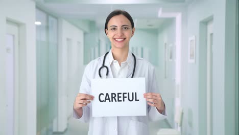 Happy-Indian-female-doctor-holding-CAREFUL-banner