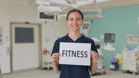 Happy-Indian-female-doctor-holding-FITNESS-banner