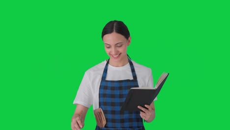 Happy-Indian-housewife-making-food-from-recipe-book-Green-screen