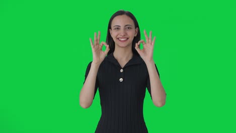 Happy-Indian-female-news-anchor-showing-okay-sign-Green-screen