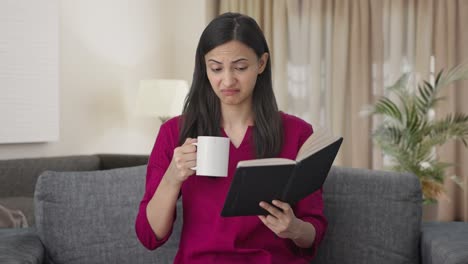 Annoyed-Indian-woman-reading-a-book-and-drinking-coffee