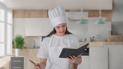 Confused-Indian-female-professional-chef-making-food-from-recipe-book