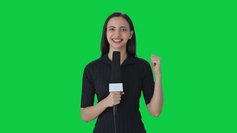 Glückliche-Indische-Nachrichtenreporterin,-Die-Mit-Dem-Grünen-Bildschirm-Der-Kamera-Spricht